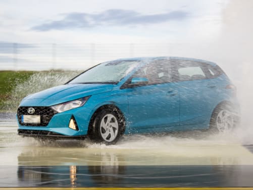 Auto fährt bei Junge-Fahrer-Training durch Wasserfontänen