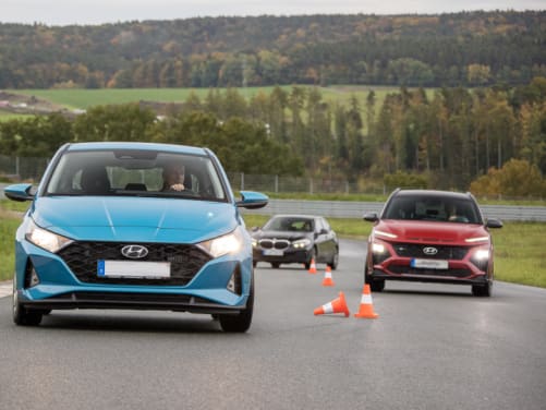 3 Autos durchfahren einen Slalomparcour in einem Fahrsicherheitstraining