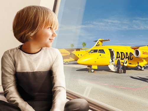 Kind sitzt am Fenster und schaut raus auf den ADAC Ambulanzjet