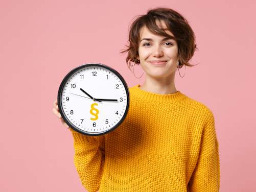 Frau zeigt Uhr mit Paragraphenzeichen und lächelt