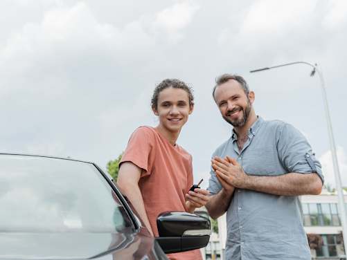 Vater und Sohn stehen neben dem Auto mit Autoschlüssel in der Hand