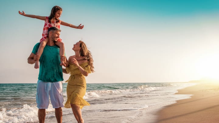 Paar mit ihrer Tochter am Strand: Auslandskrankenversicherung für Familien