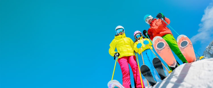 Familie beim Skifahren auf der Piste - Unfallversicherung ADAC
