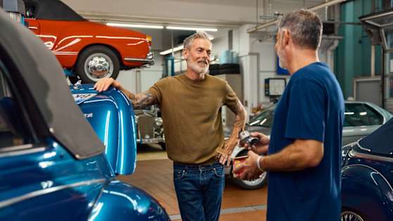 Mann unterhält sich in der Autowerkstatt mit dem Mitarbeiter