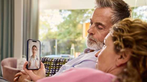 Mann und Frau nutzen das Handy für eine Online-Sprechstunde mit einem Arzt