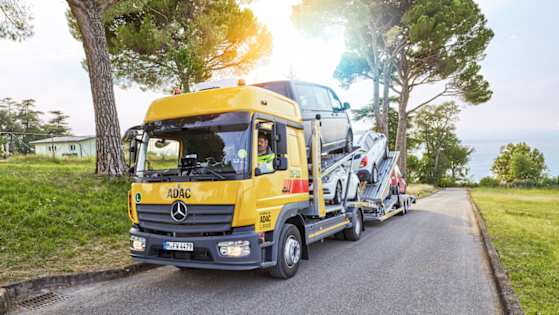 Ein ADAC-Sammeltransporter fährt an einer Straße entlang und bringt Fahrzeuge zurück.