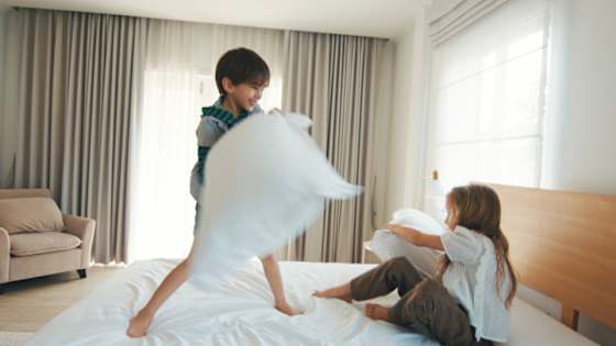 Mädchen und Jung machen Kissenschlacht im Bett - private Rechtsschutzversicherung ADAC