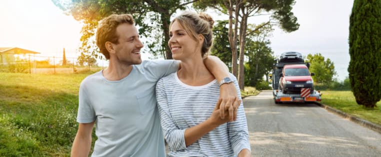 Ein glückliches Paar mit Abschleppfahrzeug im Hintergrund
