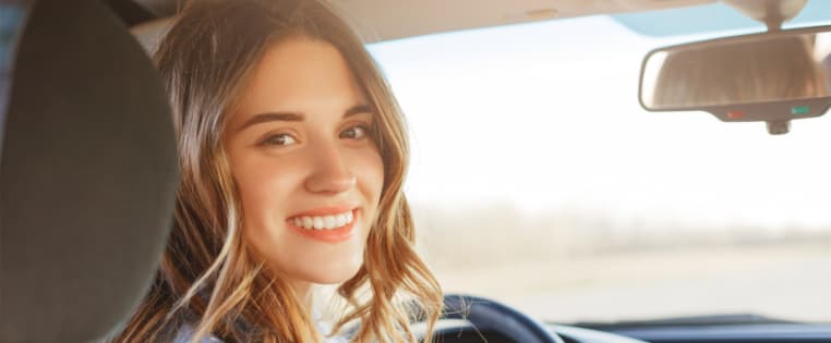 Junge Frau im Auto lächelt in die Kamera