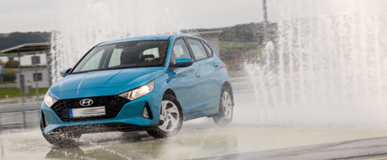 Auto fährt über Schleuderplatte durch Wasserfontänen