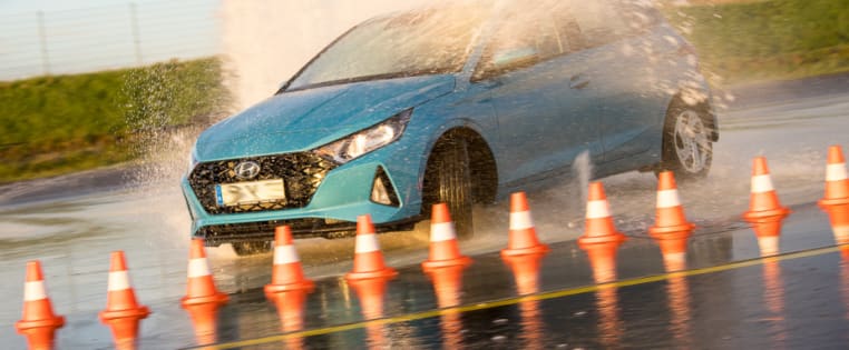 Türkises Auto fährt durch Wassersäulen beim ADAC Pkw-Intensiv-Training