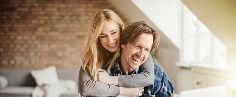 Paar sitzt vor Laptop und freut sich - private Rechtsschutzversicherung ADAC