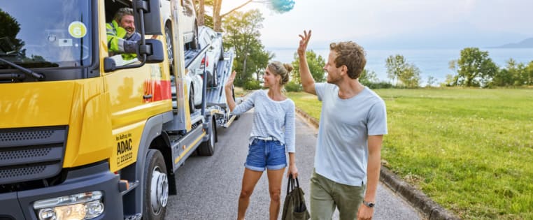 Lächelndes Paar neben einem Abschleppfahrzeug