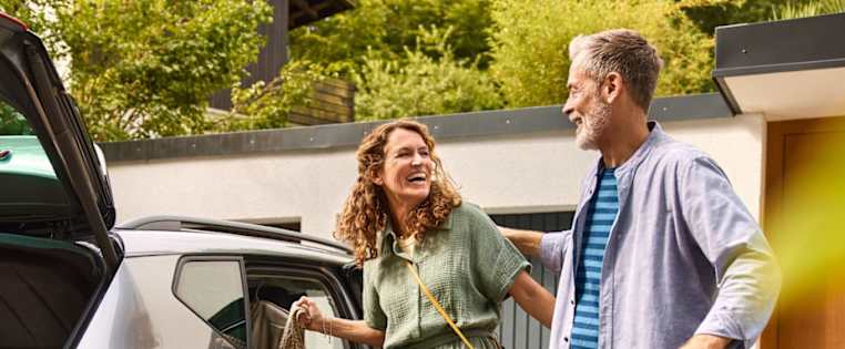 Ein Paar steht in der Einfahrt und belädt das Auto