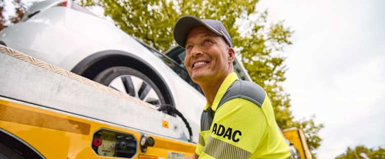 Strassenwachtfahrer lächelt und kümmert sich um das Abschleppen eines Fahrzeugs