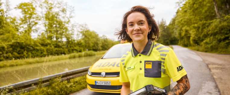 Strassenwachtfahrerin lächt, im Hintergrund ist ein ADAC Auto