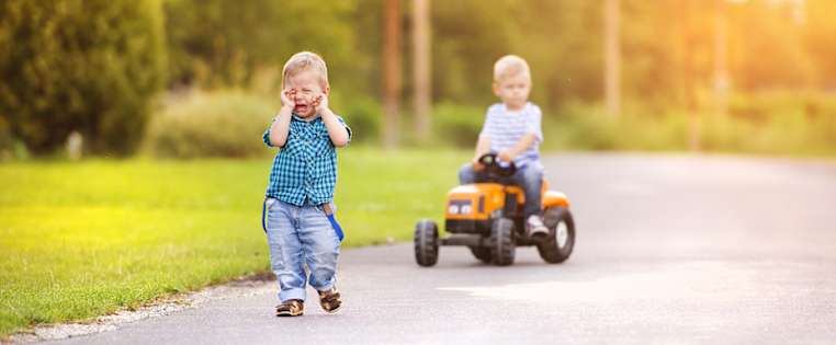 Ein Junge fährt auf Spielzeug-Traktor, ein Junge weint - Verkehrs-Rechtsschutz ADAC