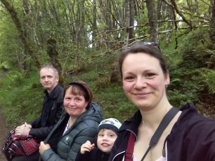 Familie sitzt lächelnd auf einer Bank in Schottland