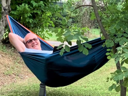 Mann liegt lächelnd in einer Hängematte