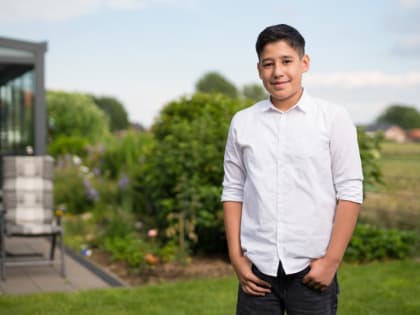 13-jähriger Junge lächelnd im Garten