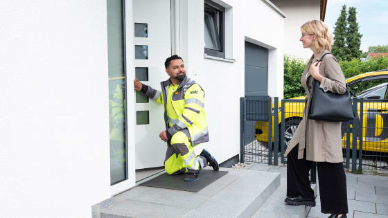 ADAC Schlüsselnotdiensthelfer öffnet einer jungen Frau die Haustür, die erleichtert ist.