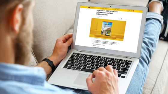 Ein Mann schaut sich die Motorweltseite auf adac.de auf seinem Laptop an