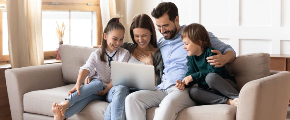 Familie auf dem Sofa betrachtet einen Laptop