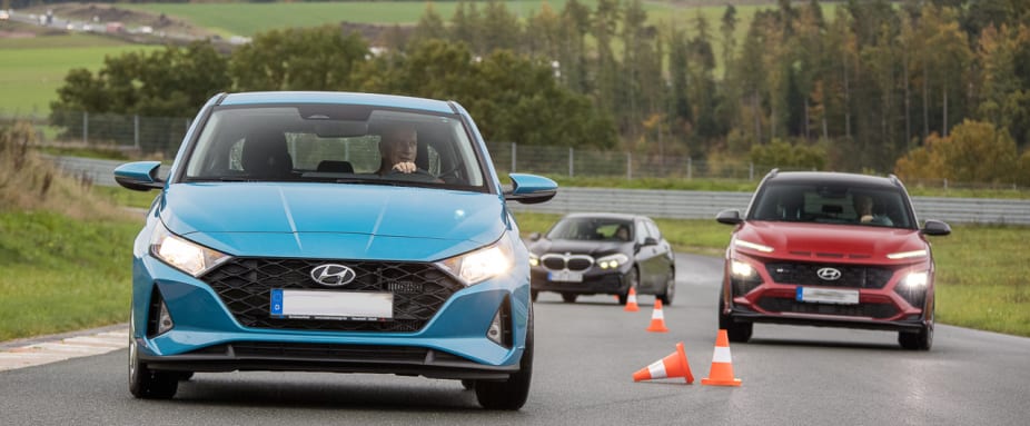 3 Autos durchfahren einen Slalomparcour in einem Fahrsicherheitstraining