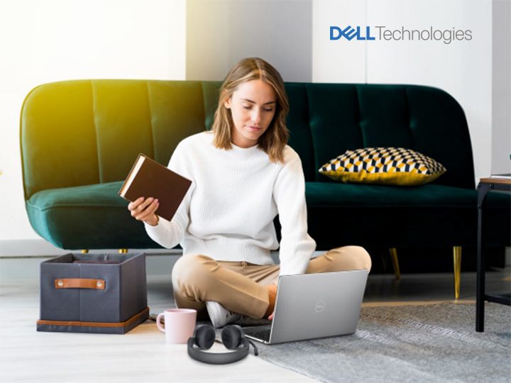 Frau sitzt mit einem DELL Laptop vor einem Sofa.