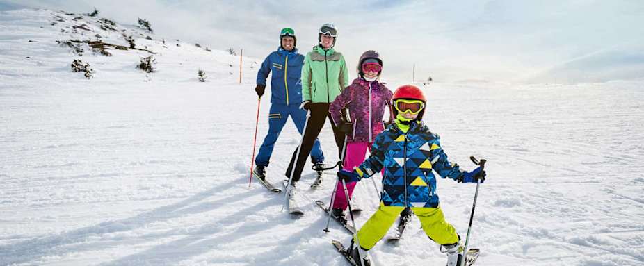 Familie steht auf Skipiste im Pflug - Unfallversicherung ADAC