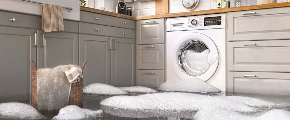 Waschmaschine in der Küche ist ausgelaufen, Wasser und Schaum auf dem Boden